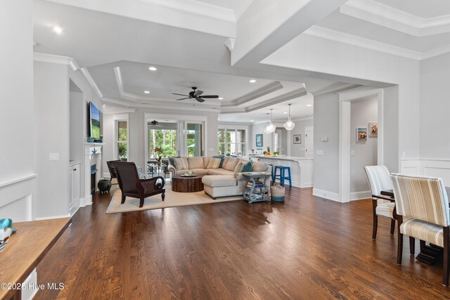 living room featuring a raised ceiling, crown molding, ceiling fan, and hardwood / wood-style flooring