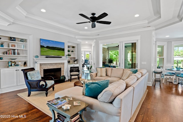 living room with a healthy amount of sunlight, a tray ceiling, ceiling fan, and ornamental molding