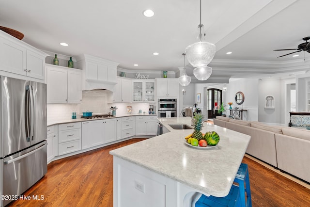 kitchen with a kitchen island with sink, white cabinetry, a breakfast bar, and stainless steel appliances