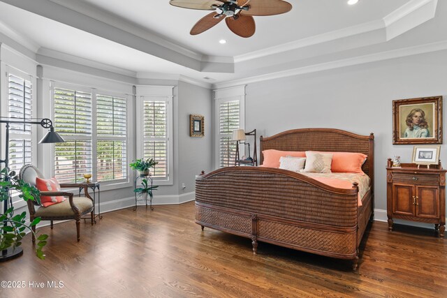 bedroom with a tray ceiling, ceiling fan, dark wood-type flooring, and ornamental molding