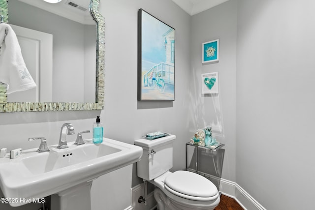 bathroom featuring crown molding, sink, wood-type flooring, and toilet