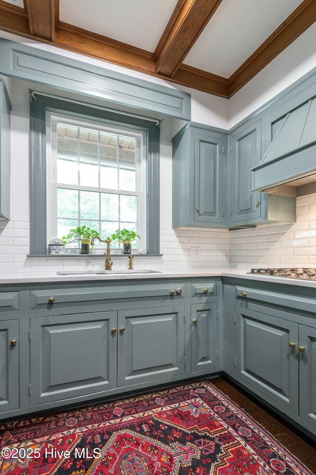 kitchen featuring sink, gray cabinetry, decorative backsplash, ornamental molding, and gas stovetop