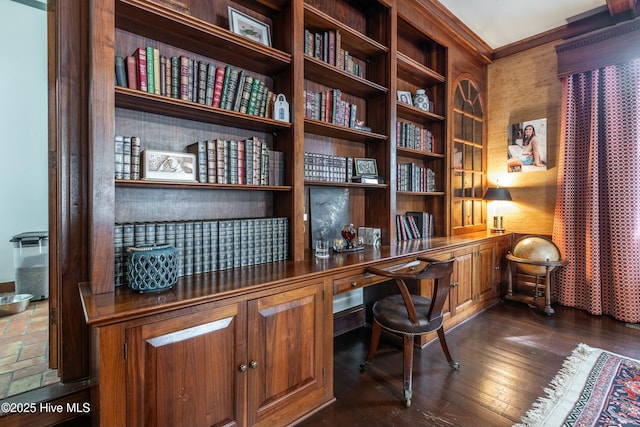 office space with built in desk, ornamental molding, and dark hardwood / wood-style floors