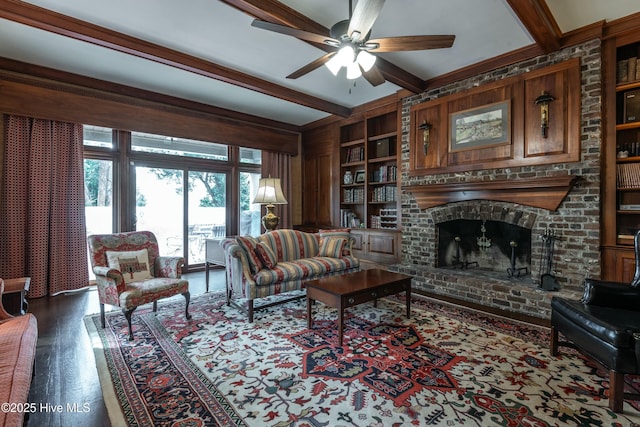 living room featuring built in features, ceiling fan, beam ceiling, dark hardwood / wood-style flooring, and a brick fireplace