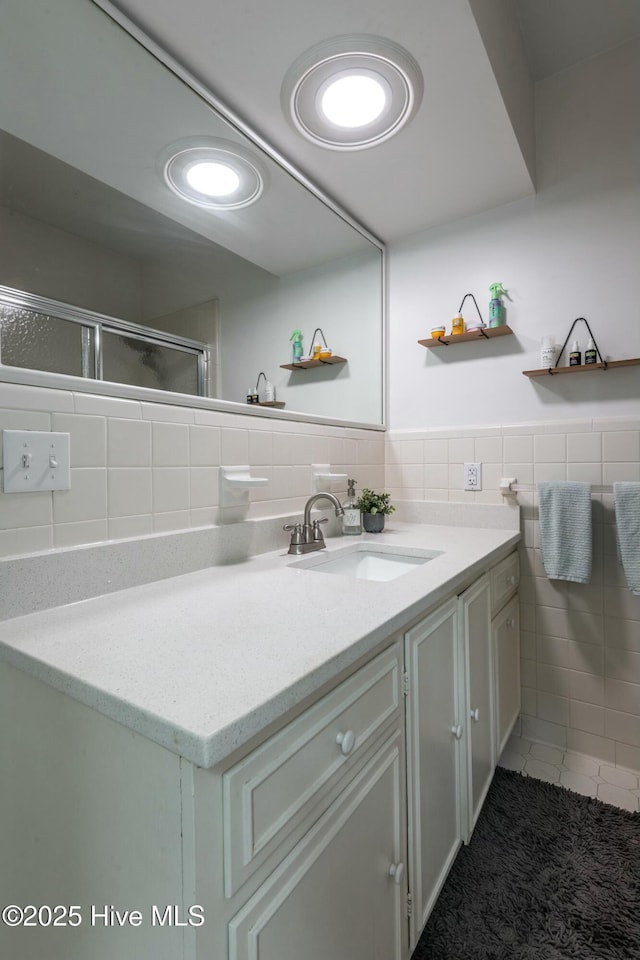 bathroom with tile patterned flooring, vanity, tile walls, and an enclosed shower