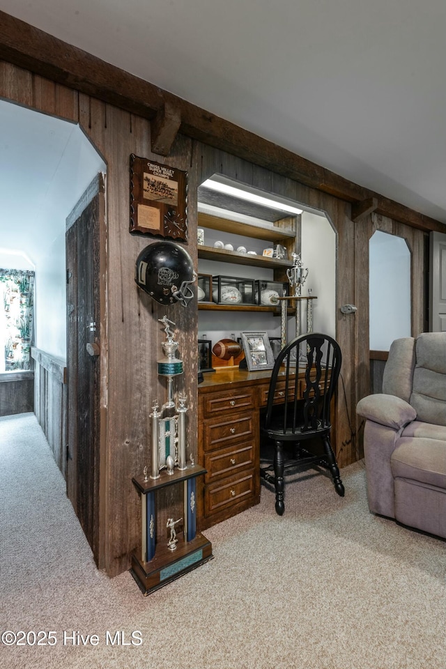 carpeted living room with wood walls