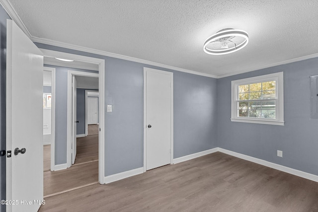 unfurnished bedroom featuring ornamental molding, a textured ceiling, light wood-type flooring, and a closet