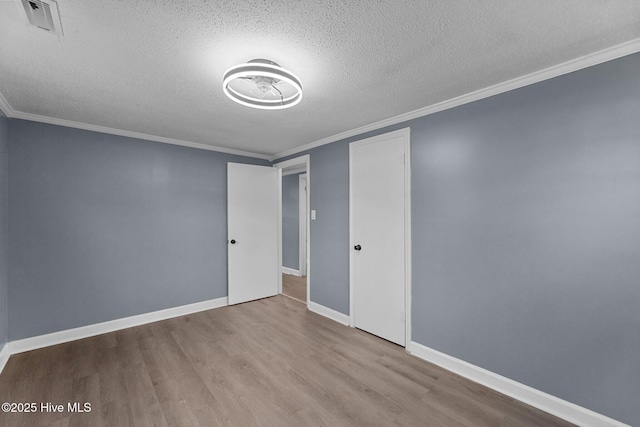 spare room featuring crown molding, a textured ceiling, and light hardwood / wood-style flooring