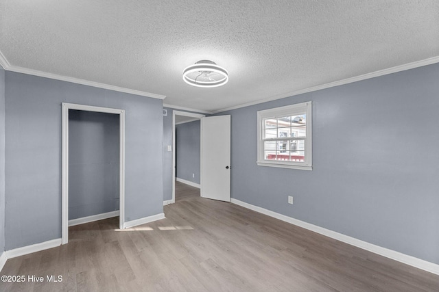 unfurnished bedroom featuring crown molding, light hardwood / wood-style floors, a closet, and a textured ceiling