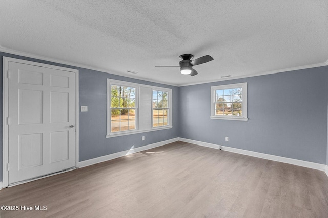 empty room featuring wood-type flooring, ornamental molding, and a textured ceiling