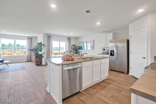 kitchen featuring light wood-type flooring, stainless steel appliances, sink, a center island with sink, and white cabinets