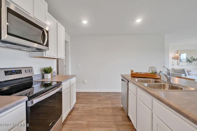 kitchen with stainless steel appliances, light countertops, white cabinetry, and a sink