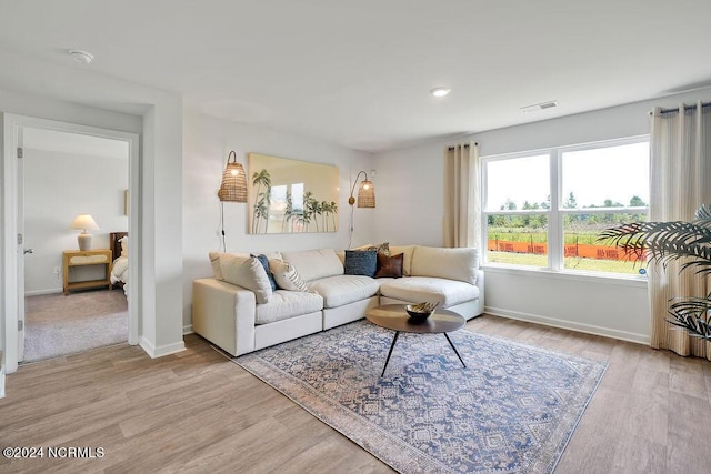 living area with light wood-style flooring, visible vents, and baseboards