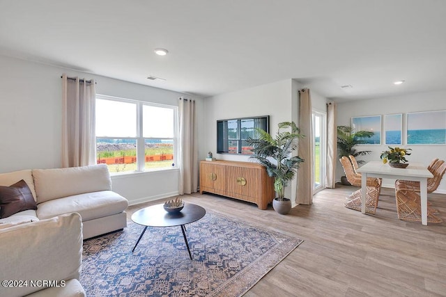 living area with light wood-type flooring, plenty of natural light, baseboards, and recessed lighting