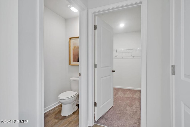 bathroom featuring toilet, a spacious closet, and baseboards