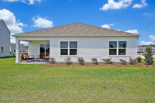 back of property with roof with shingles, a lawn, and a patio