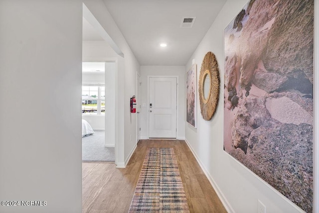 corridor featuring light wood-type flooring, baseboards, and visible vents