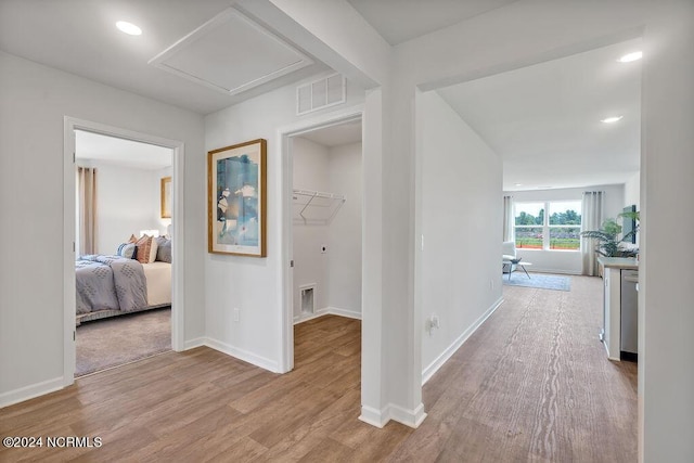 hall featuring light wood-type flooring, baseboards, visible vents, and recessed lighting