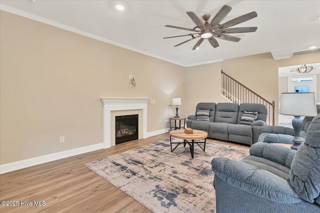 living room with hardwood / wood-style floors, ceiling fan, and ornamental molding