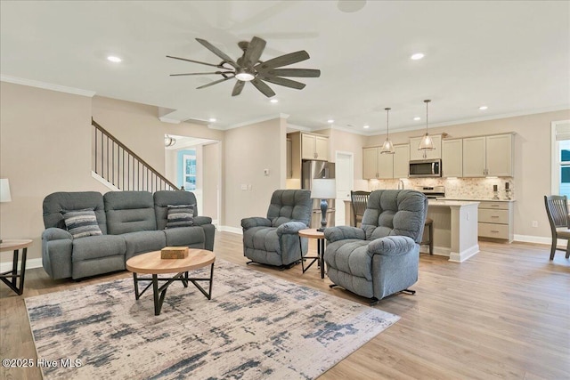 living room with light wood-type flooring, ceiling fan, and ornamental molding