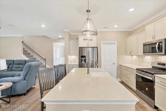 kitchen featuring appliances with stainless steel finishes, tasteful backsplash, a kitchen island with sink, sink, and decorative light fixtures