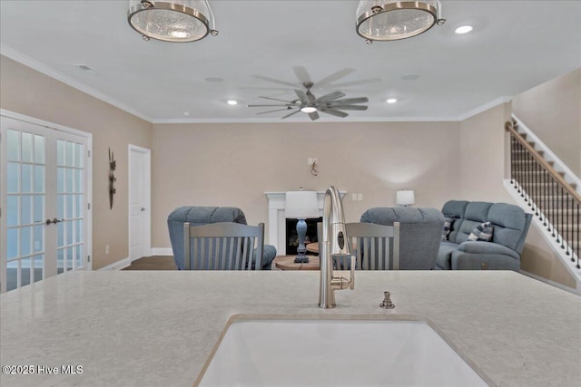 living room featuring ceiling fan, sink, and ornamental molding