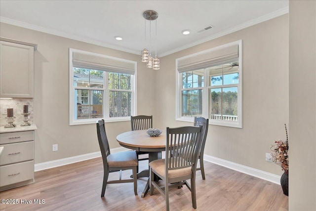 dining space featuring light wood-type flooring, ornamental molding, and a chandelier