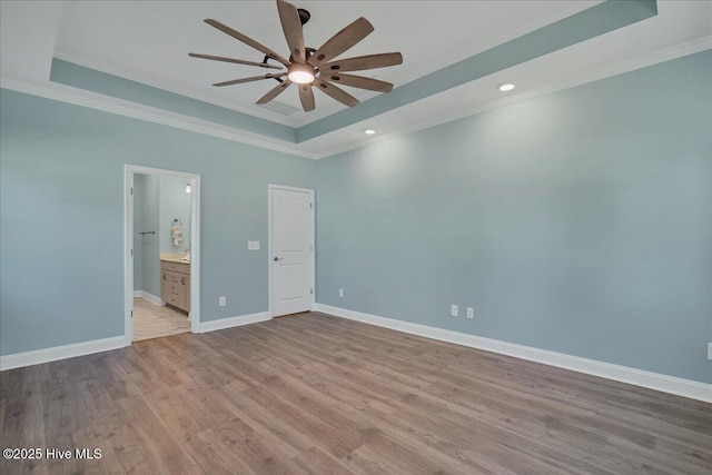 unfurnished bedroom featuring ornamental molding, a tray ceiling, ceiling fan, connected bathroom, and light hardwood / wood-style floors