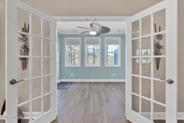 unfurnished dining area featuring crown molding, french doors, ceiling fan, and light hardwood / wood-style floors