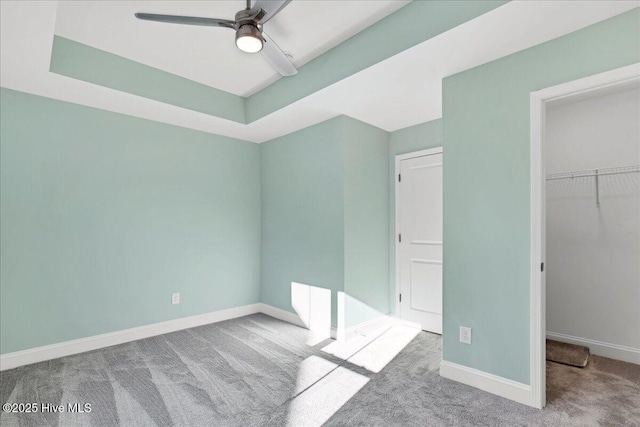 unfurnished bedroom with light carpet, a closet, ceiling fan, and a tray ceiling