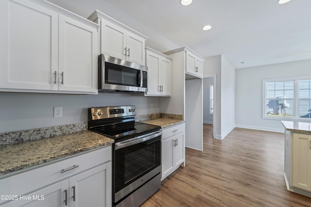 kitchen featuring light hardwood / wood-style flooring, light stone countertops, stainless steel appliances, and white cabinetry