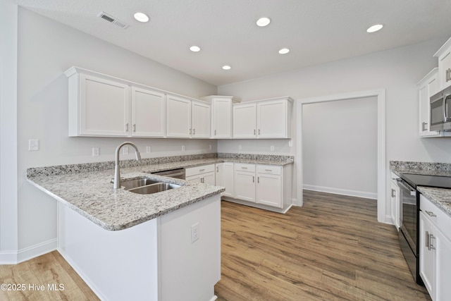 kitchen featuring white cabinetry, kitchen peninsula, appliances with stainless steel finishes, light hardwood / wood-style flooring, and sink