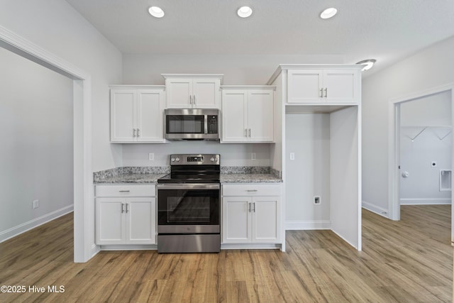 kitchen with appliances with stainless steel finishes, light hardwood / wood-style flooring, and white cabinetry