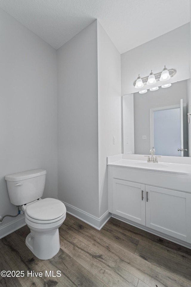 bathroom with toilet, wood-type flooring, and vanity