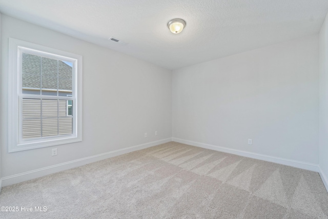 empty room featuring light colored carpet and a textured ceiling