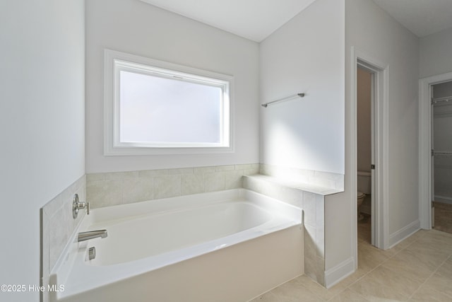 bathroom with toilet, tile patterned flooring, and a bathtub