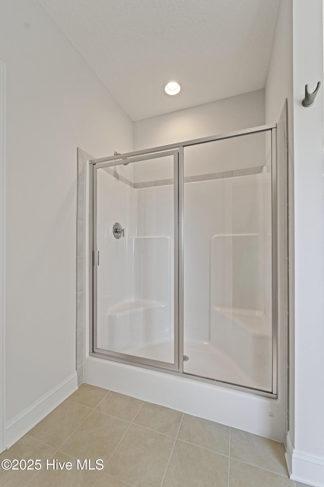 bathroom with a textured ceiling, tile patterned floors, and a shower with shower door