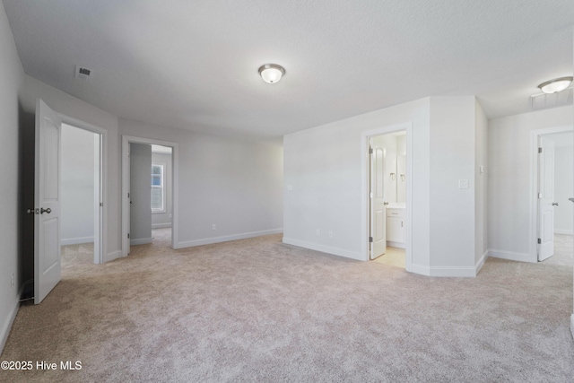 unfurnished bedroom with light colored carpet and connected bathroom