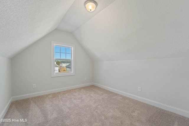 additional living space with a textured ceiling, vaulted ceiling, and carpet floors