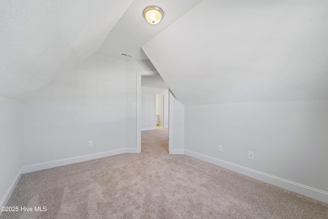 bonus room with a textured ceiling, light carpet, and vaulted ceiling