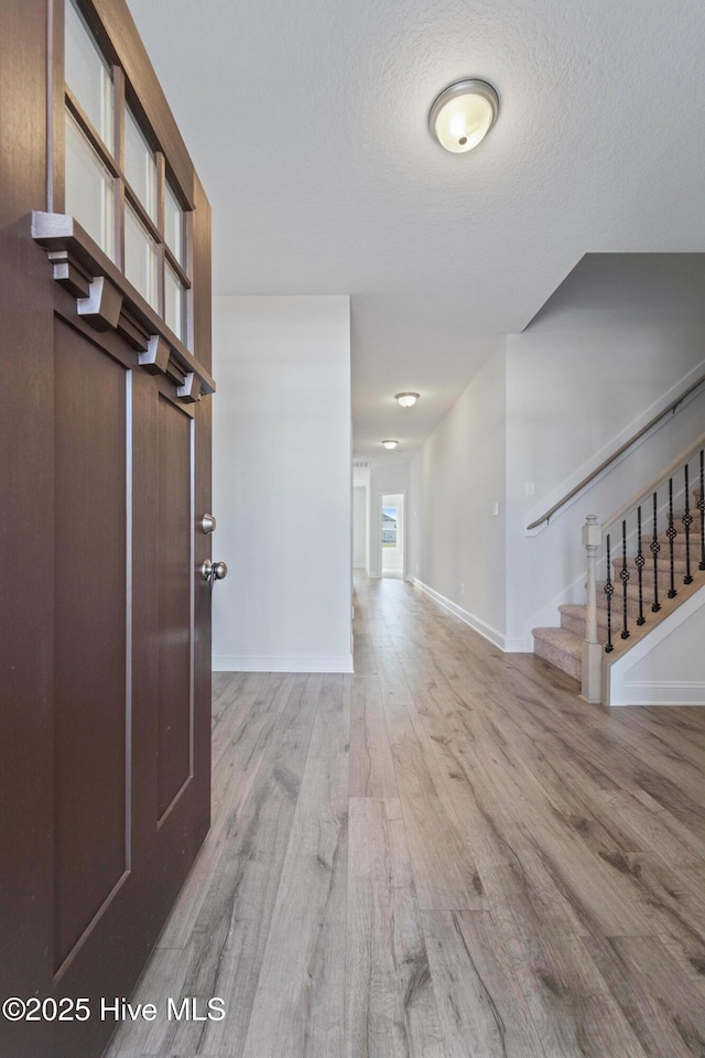 interior space with a textured ceiling and light hardwood / wood-style flooring