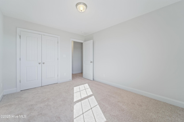 unfurnished bedroom with a closet and light colored carpet