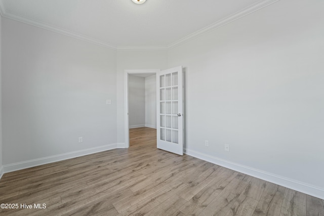 empty room featuring light hardwood / wood-style flooring, ornamental molding, and french doors