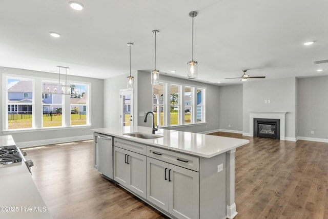 kitchen with pendant lighting, sink, a kitchen island with sink, stainless steel dishwasher, and a healthy amount of sunlight