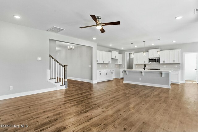 kitchen featuring white cabinetry, a center island with sink, hanging light fixtures, sink, and appliances with stainless steel finishes