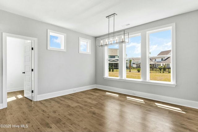 unfurnished dining area featuring hardwood / wood-style flooring and a chandelier