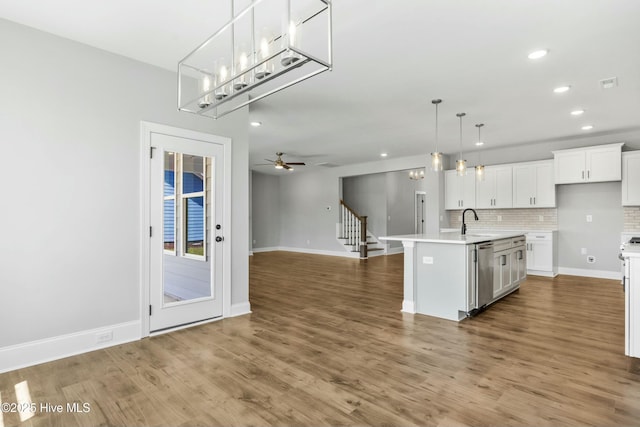 kitchen with pendant lighting, an island with sink, white cabinets, decorative backsplash, and stainless steel dishwasher