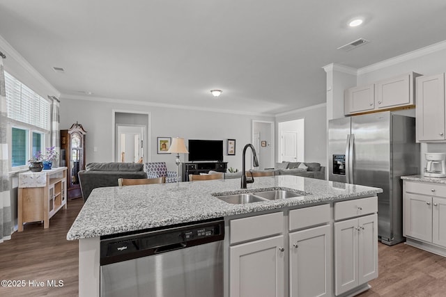 kitchen with white cabinetry, sink, an island with sink, appliances with stainless steel finishes, and ornamental molding