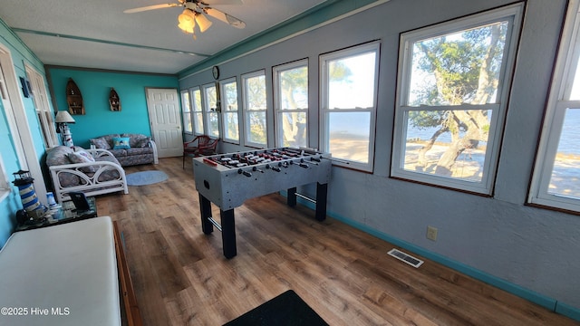 recreation room featuring ceiling fan, a healthy amount of sunlight, and hardwood / wood-style flooring