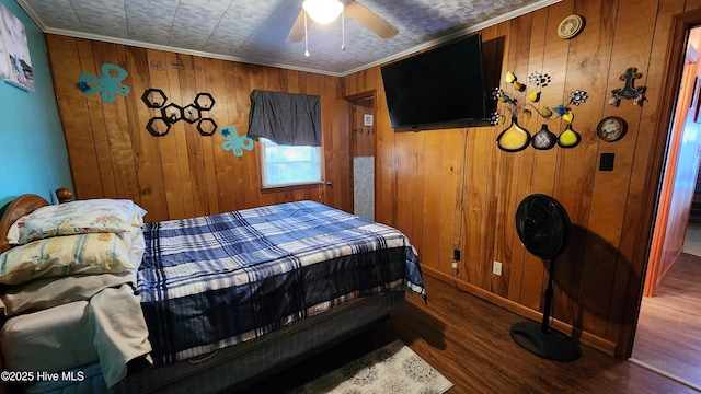 bedroom with ceiling fan, wood walls, and ornamental molding